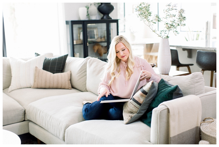 Arizona Brand Photographer Denise Karis Woman with blond hair and a pink top sits on a sofa looking at a photo album