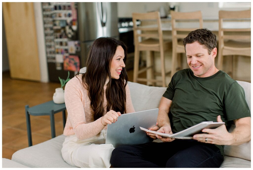 Arizona Brand Photographer couple sits on a sofa looking at a computer 