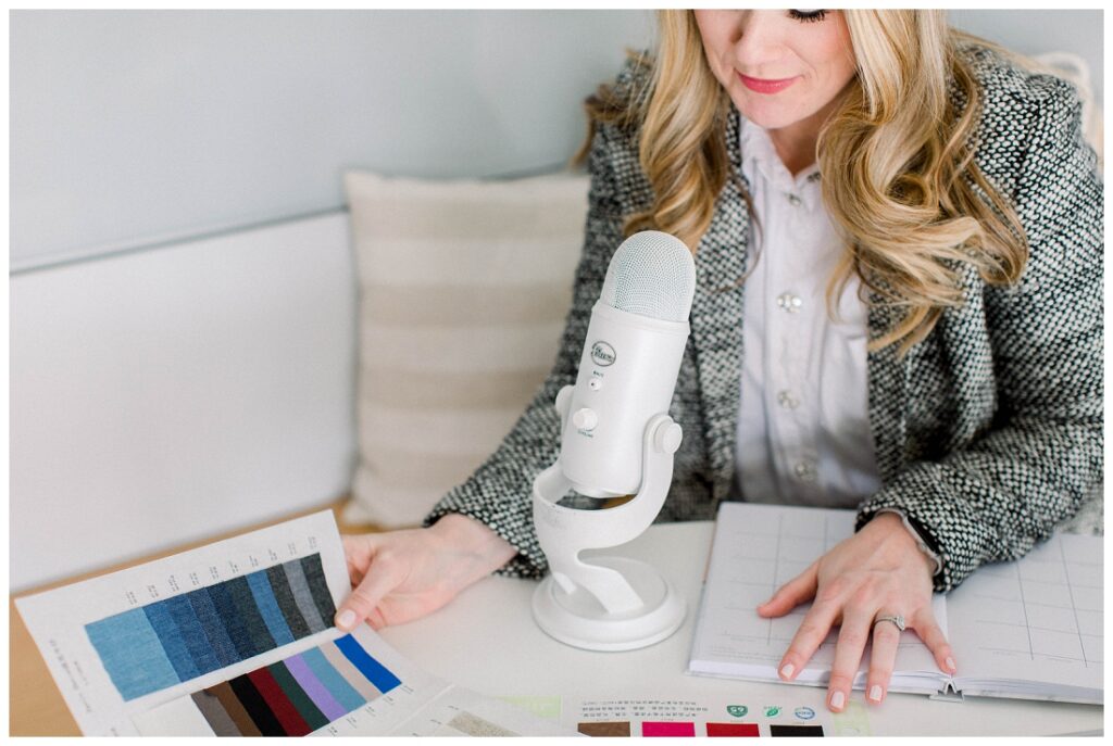 Woman at a desk looks over color swatches and speaks into a podcast microphone Denise Karis brand photography 