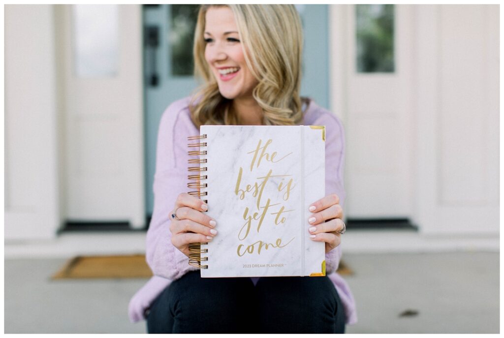 Denise Karis brand photography woman in purple holds out a planner that says "The best is yet to come" 