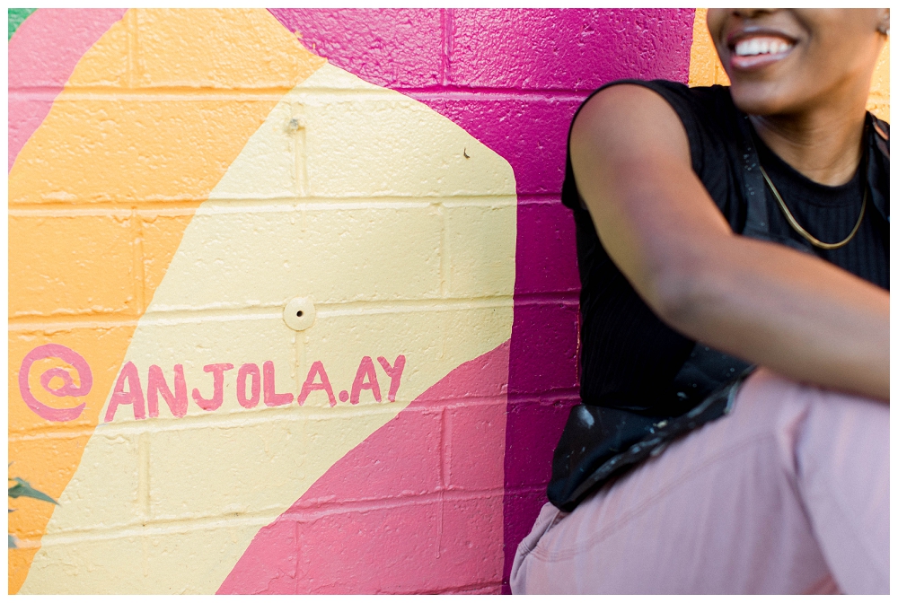 an image of a mural with the muralist's Instagram tag, the artist sits off to the side. 