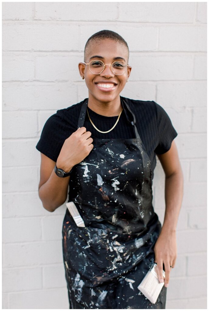 A painter in a painters apron smiles at the camera. 