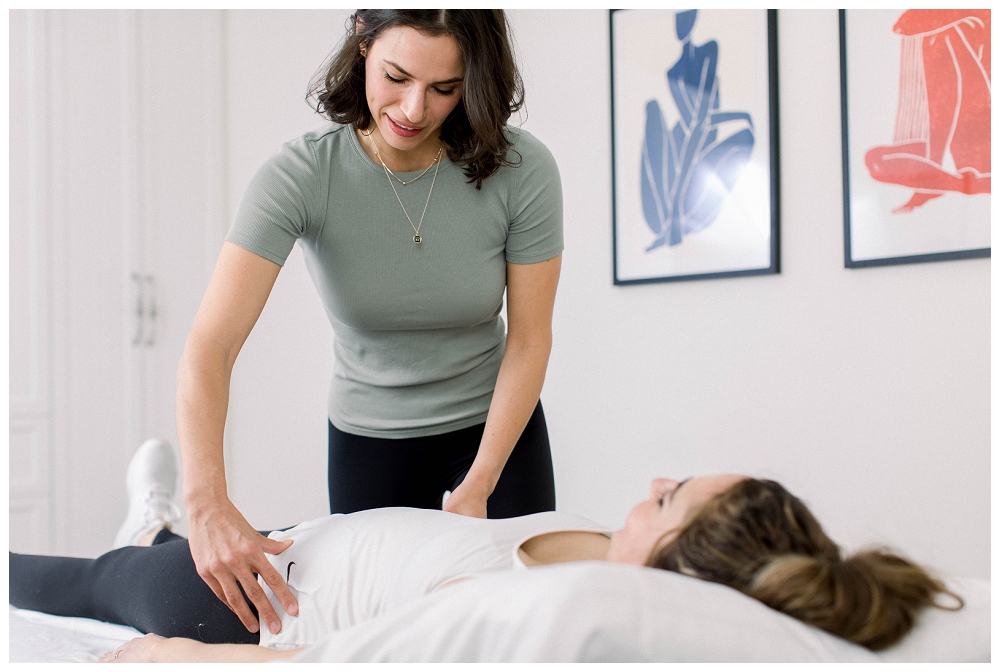 A physical therapist feels the stomach of a patient who is lying on a treatment table. 