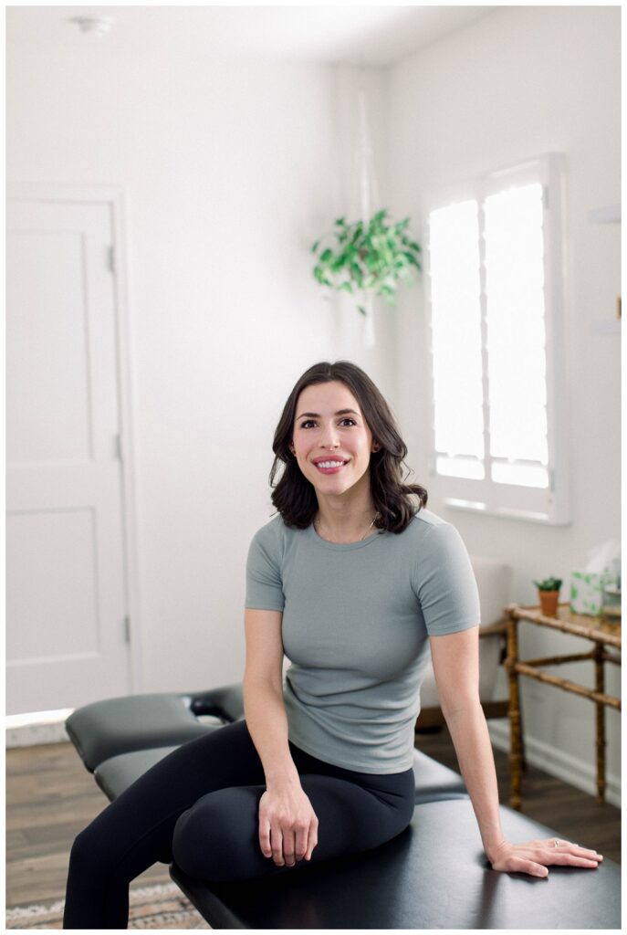 A woman sits on a treatment table in a home therapy setting.