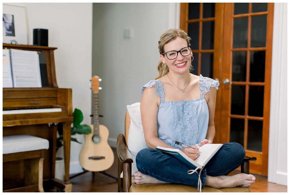 Branding portrait of a woman smiling at the camera with a journal open in her lap. 