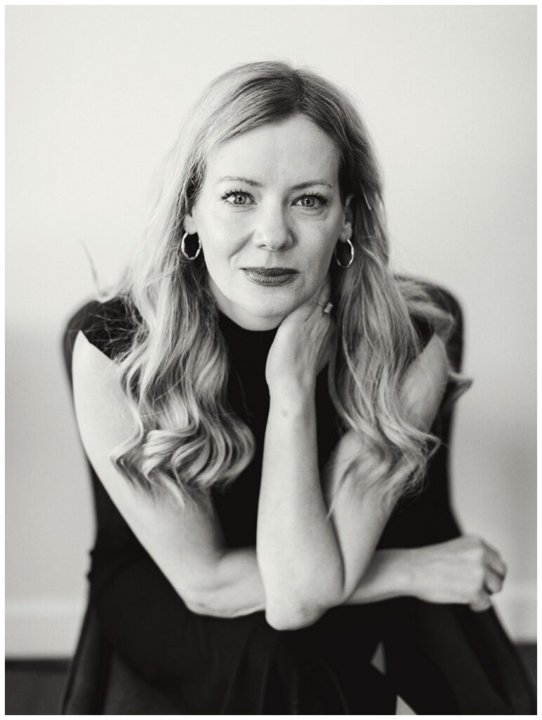 Black and white portrait of a woman with blond hair and a black outfit. 