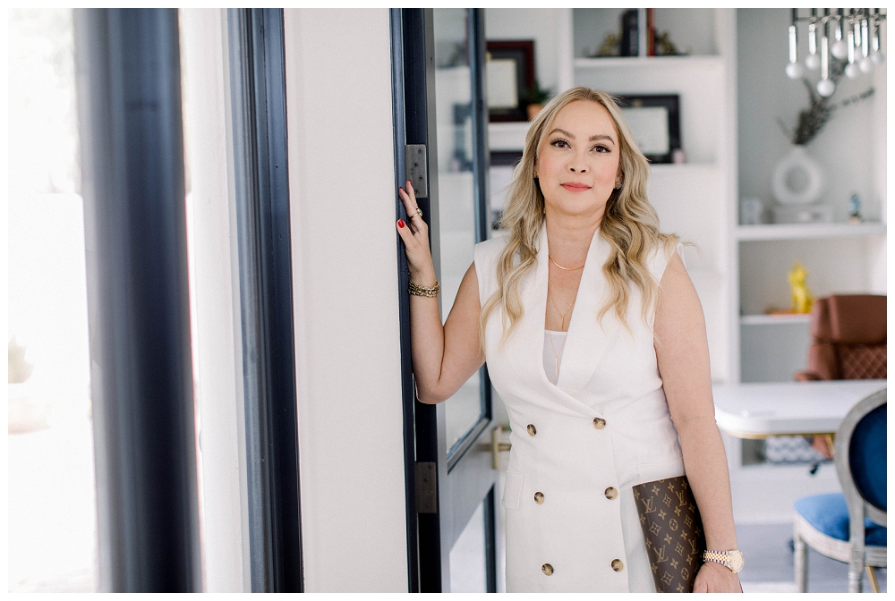 A woman in a beige outfit leans against a door frame
