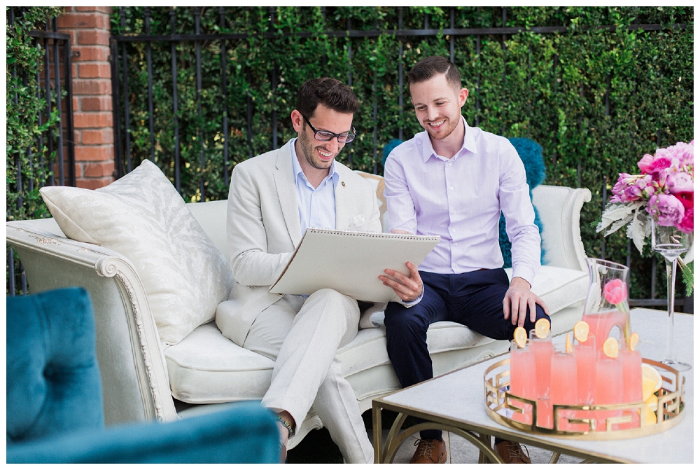 Two well dressed men work on a design sketch while sitting on a sofa. 