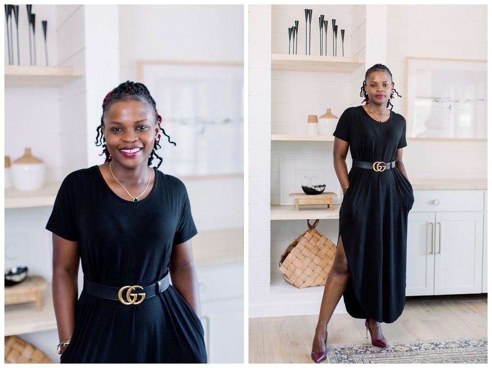 A woman in a dark dress stands in a living room. She smiles at the camera. 