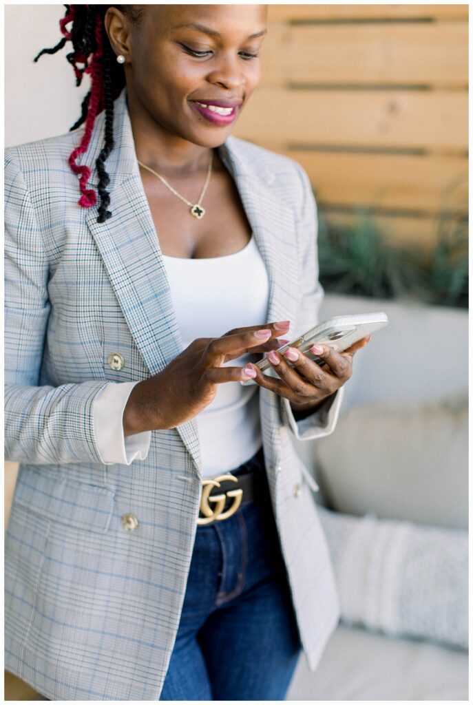 A womain wearing a grey blazer and jeans scrolls on a cell phone. 