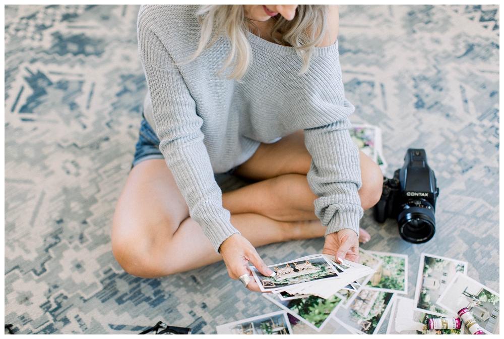 A woman sits on the floor looking at printed photos