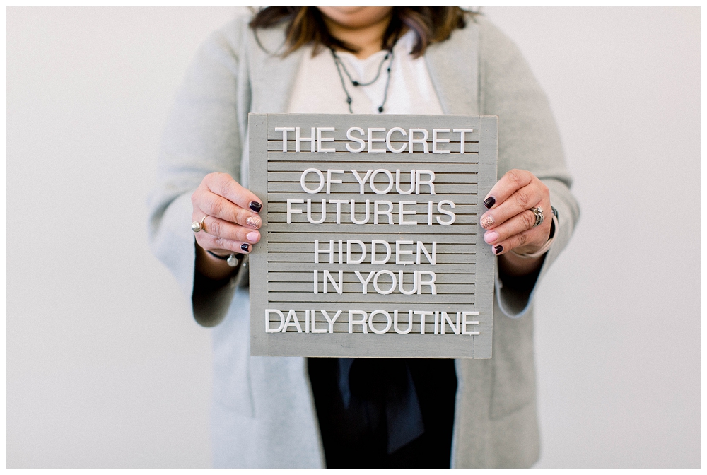 Branding portrait a woman holds a sign that says "The secret of your future is hidden in your daily routine"