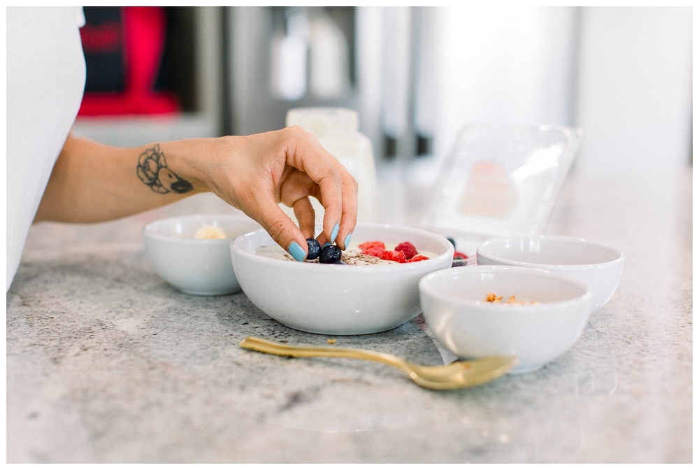 bowls of oatmeal and berries, a hand is picking a berry from one of the bowls. 