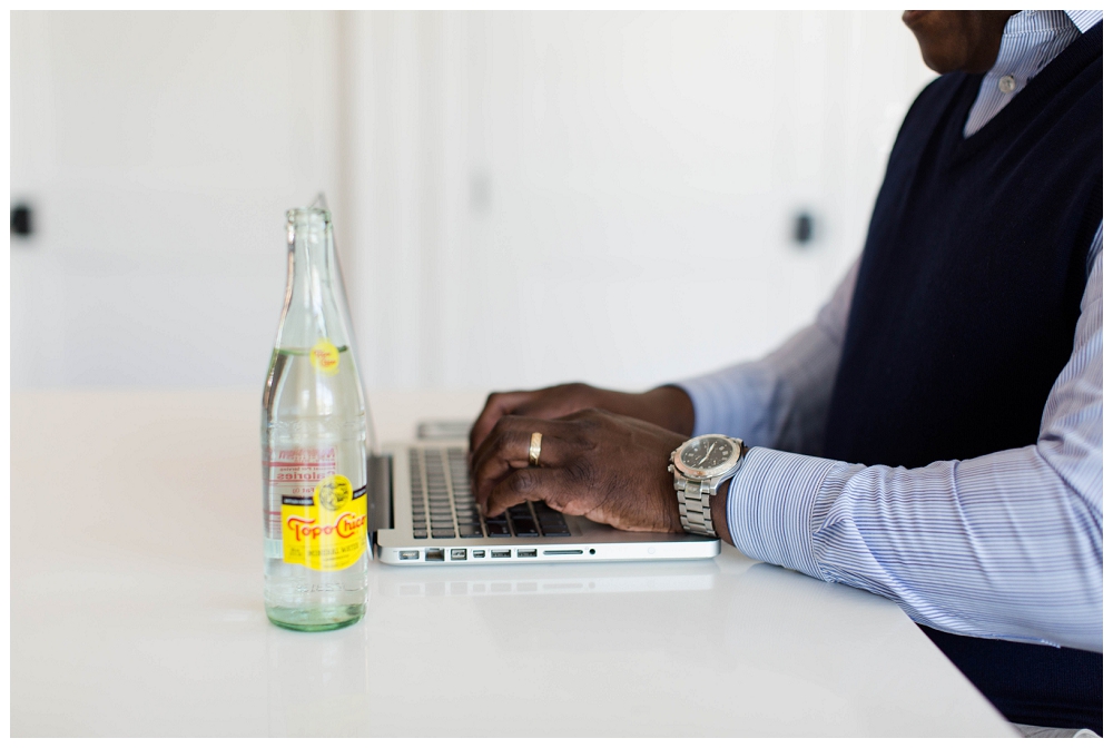 hands type on a keyboard. A topo chico bottle is open on the table. 