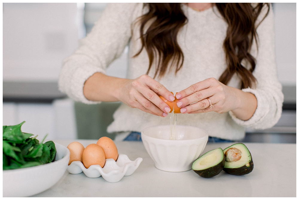 A woman cracks an egg into a bowl. 