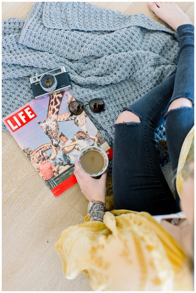A woman sits on the floor with a coffee and a vintage life magazine 