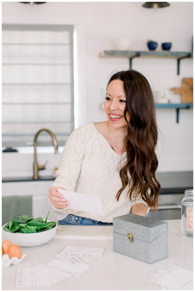 A woman looks over recipe cards in a kitchen. 