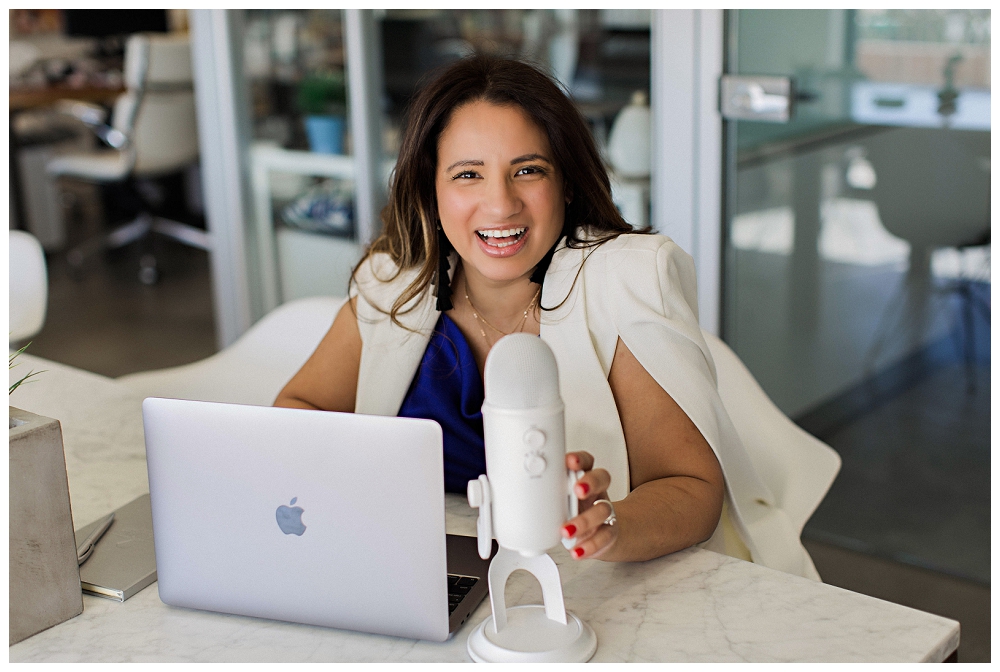 Branding Portrait a woman smiles while speaking into a podcast mic. 