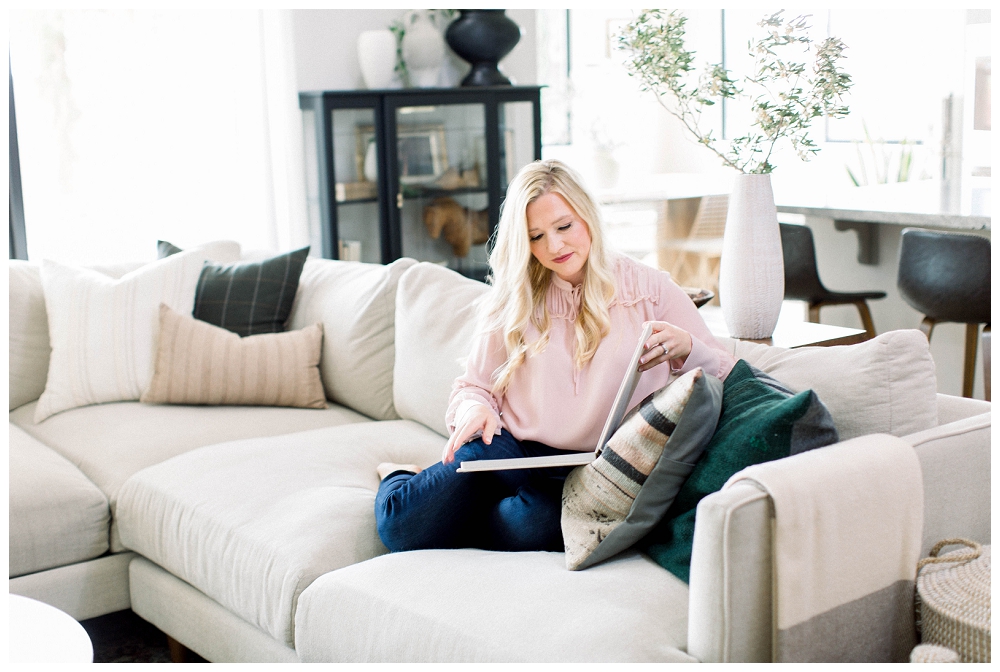 Branding Portrait A woman sits on a sofa looking at a photo album. 