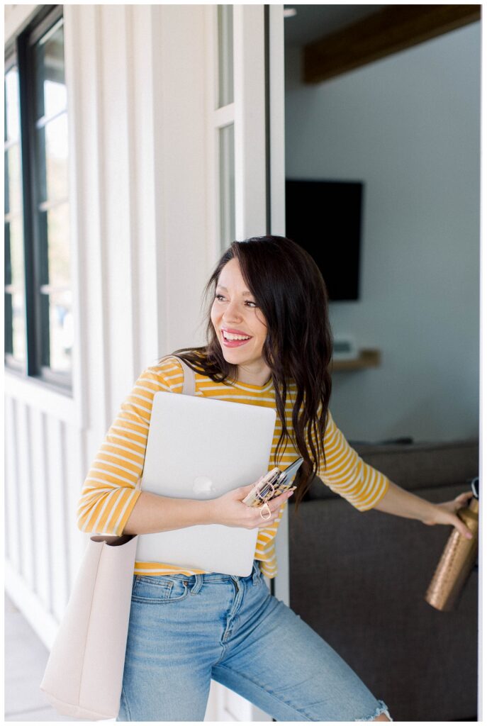 Branding Portrait a woman is walking into a house carrying a notebook. 