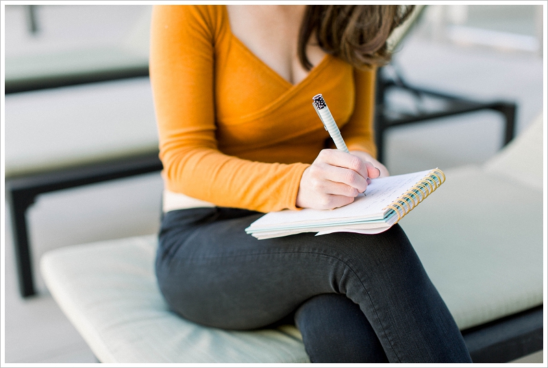 Woman writing in a journal in an orange sweater