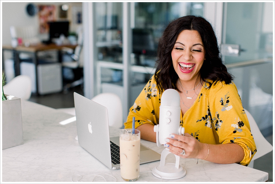 Brand Photography woman sitting at a desk with coffee, laptop, and podcast microphone