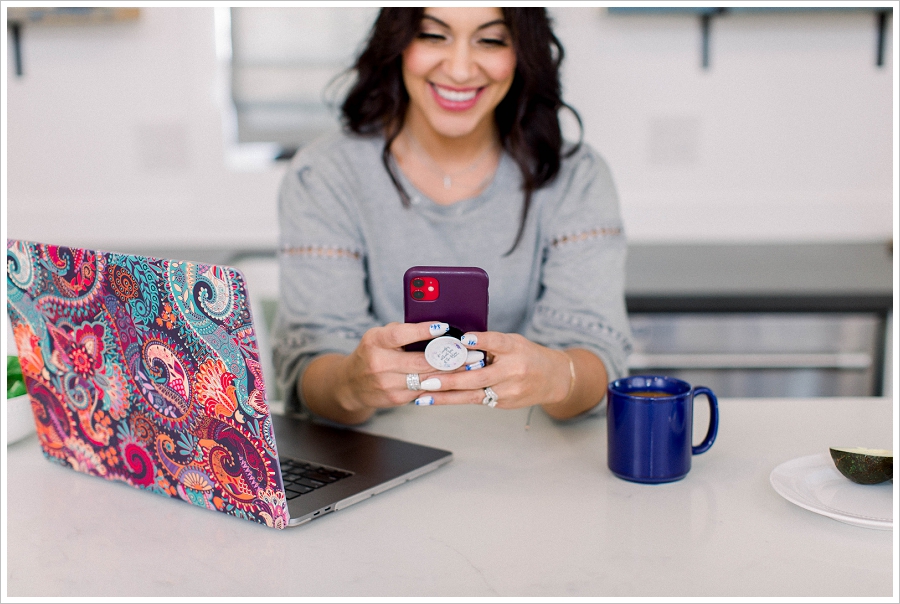 Brand Photography Woman on cell phone next to laptop with coffee