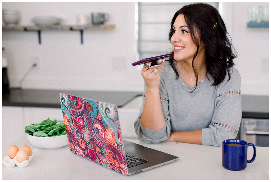 Brand Photography Woman speaking into phone with a laptop on the counter