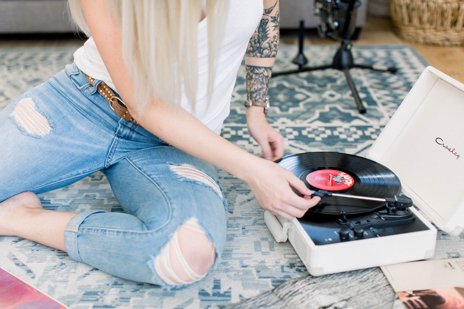 Branding image of a woman setting a record on a portable turntable.
